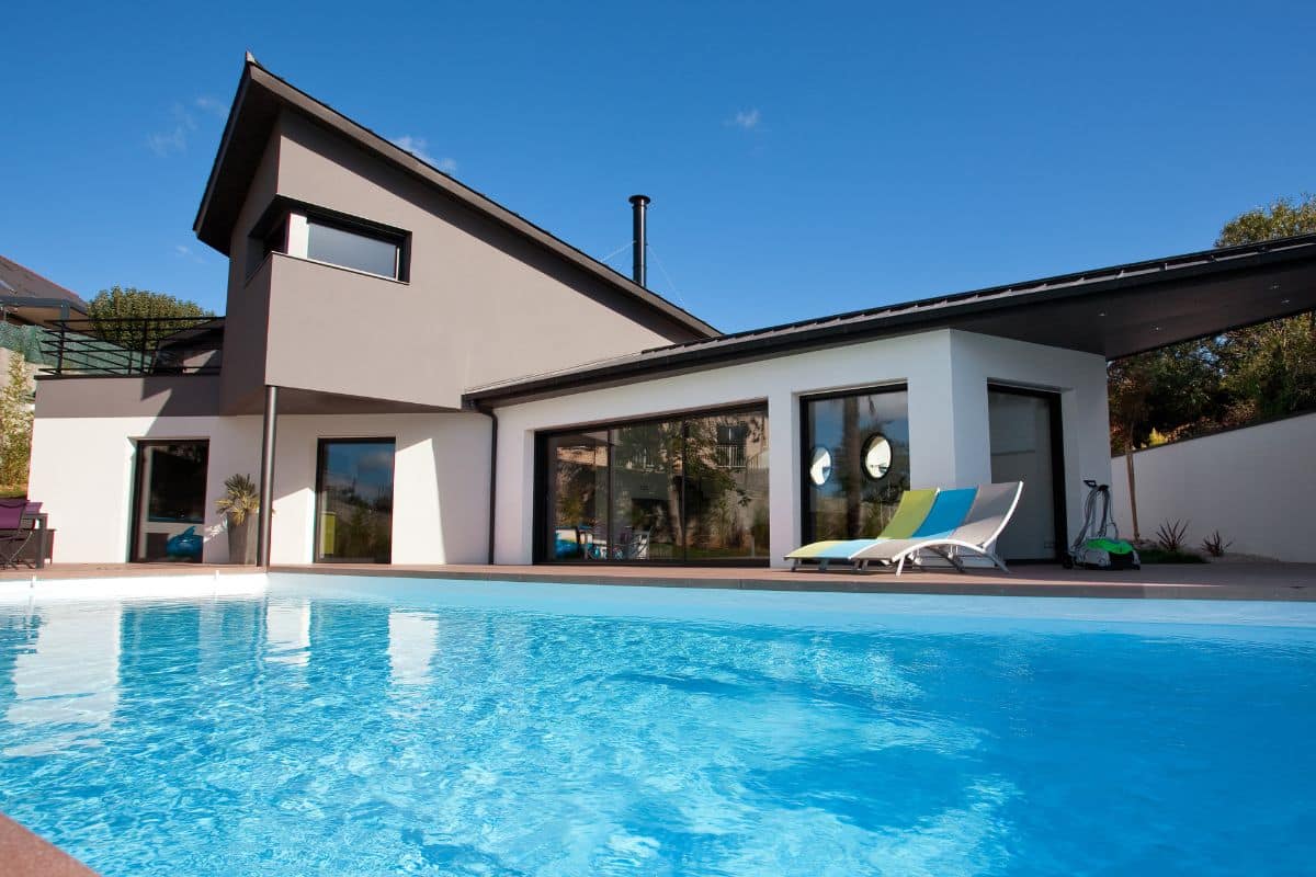 Maison neuve avec une baie vitrée aluminium 3 vantaux donnant sur une piscine.